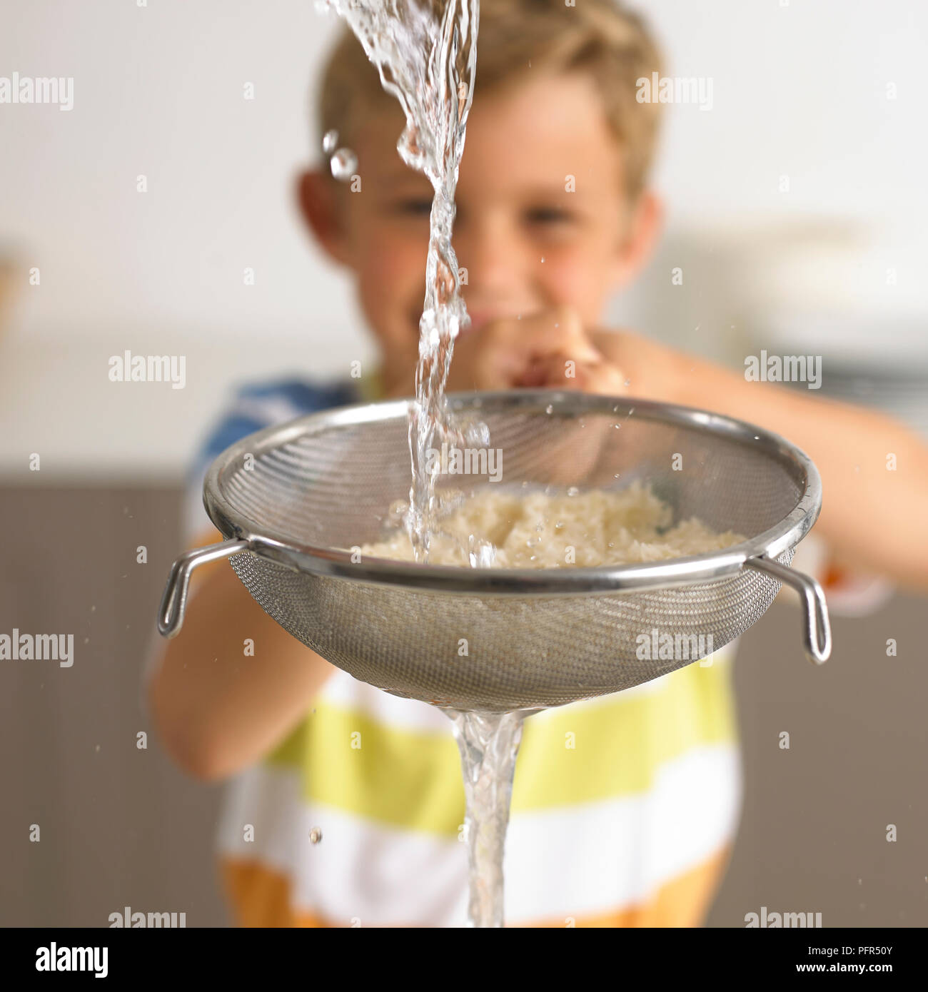 Washing rice in a sieve with water, 6 years Stock Photo