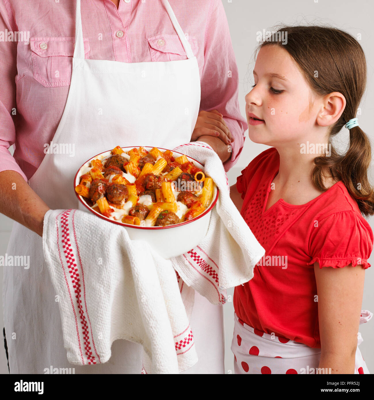 Girl looking at pasta, meatball and cheese bake, 7 years Stock Photo