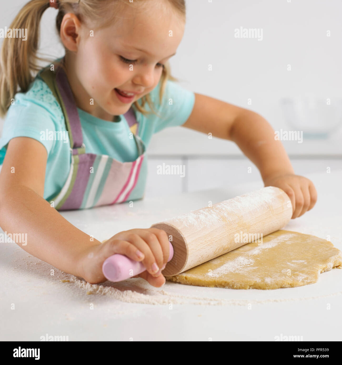 Girl rolling out cookie dough, 5 years Stock Photo