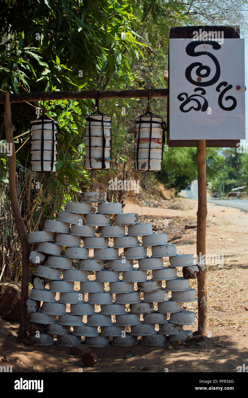 Sri Lanka, Uva Province, Wellawaya, stack of pans and sign on roadside Stock Photo