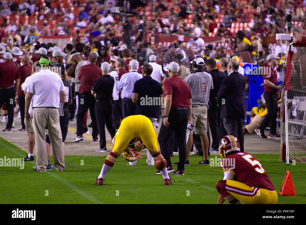 Redskin players on sideline practicing for extra point kick at preseason game Stock Photo