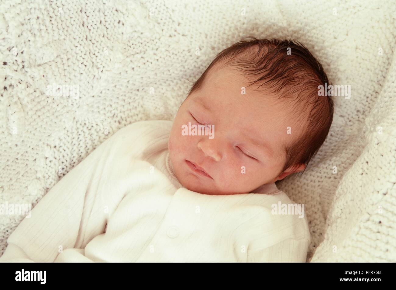 Newborn baby girl lying on blanket with her eyes closed Stock Photo
