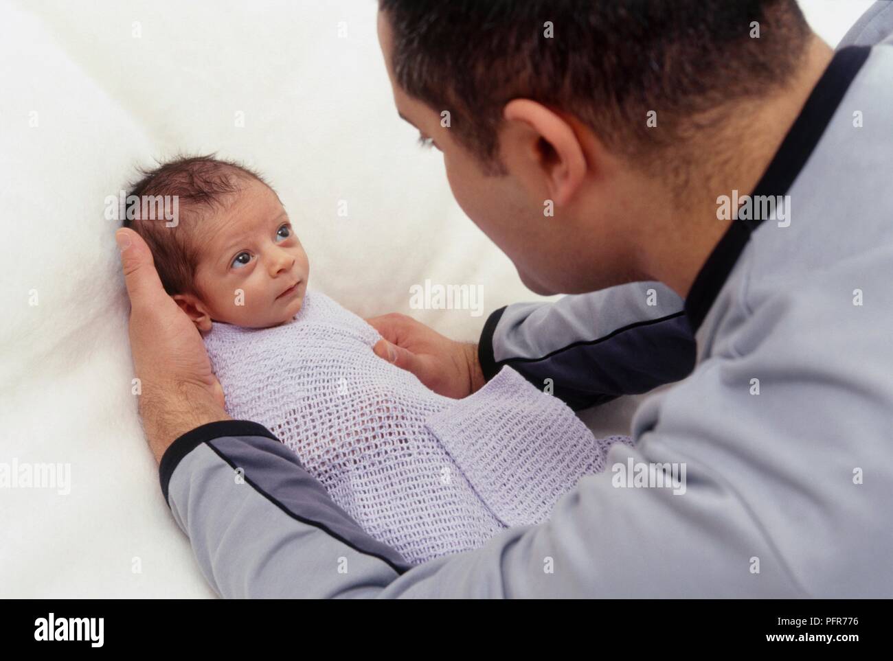 Man wrapping baby boy in blanket, close-up Stock Photo