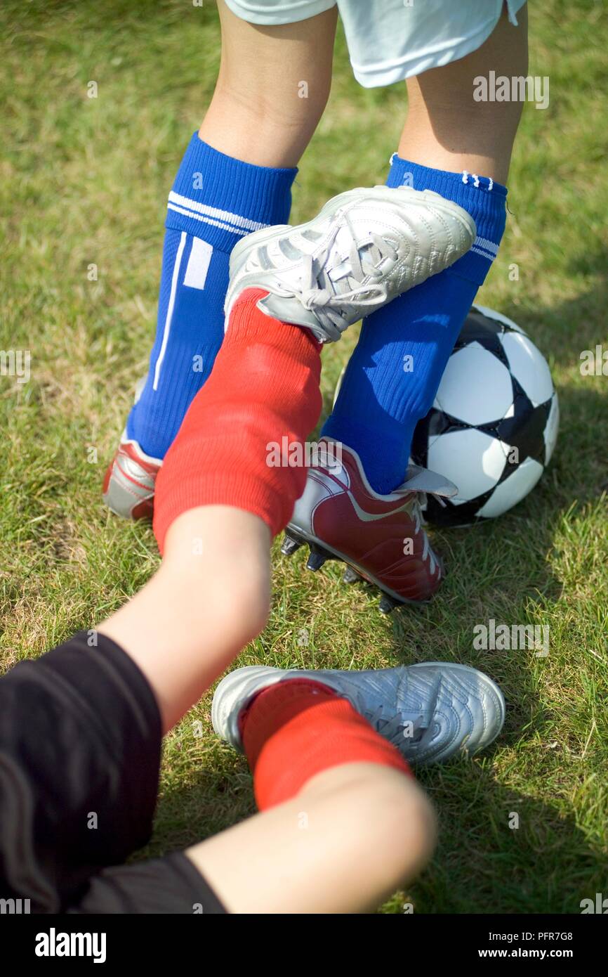 Close-up on feet of young football player tackling another from