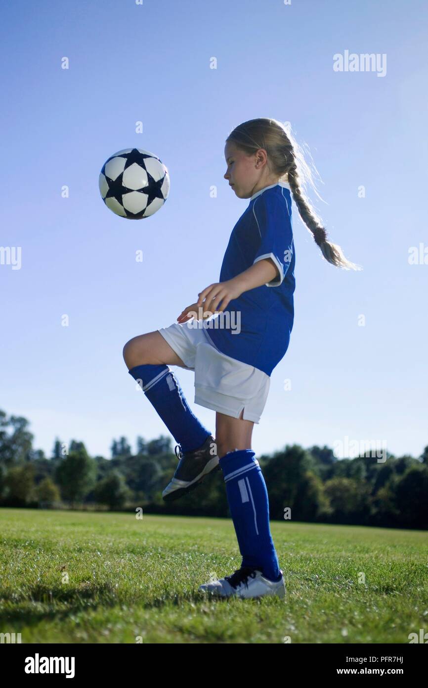 Young female football player controlling football using thigh Stock