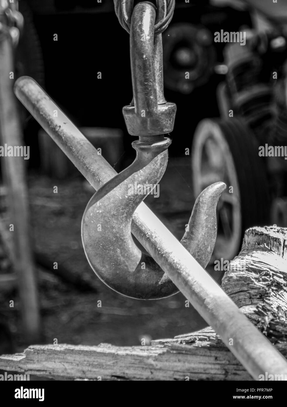 Black & white image of an industrial hook with a lead pipe through the hook Stock Photo