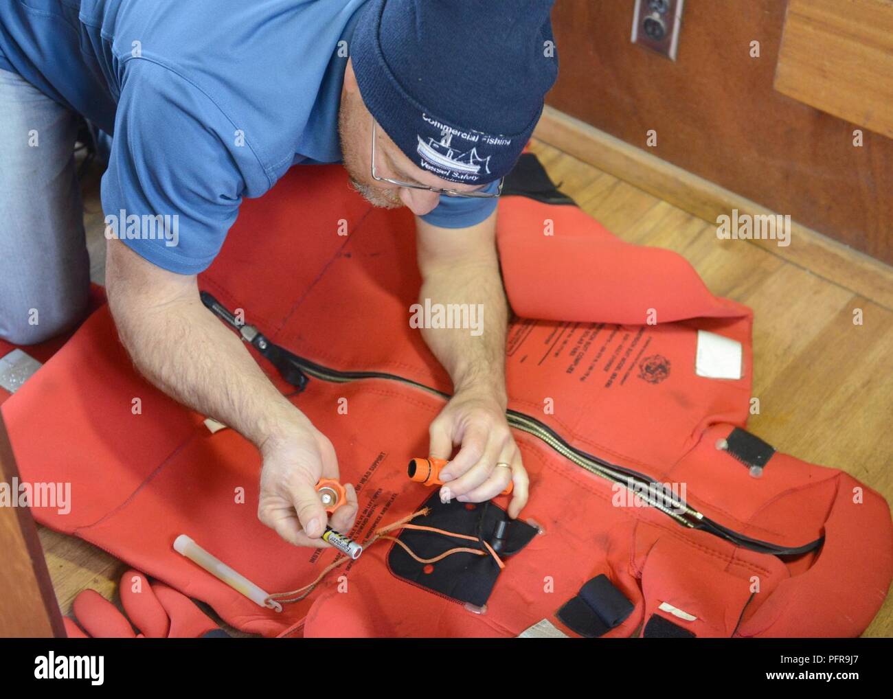 Dennis Schoenwether, a Coast Guard commercial fishing vessel safety examiner, carefully inspects an immersion suit aboard a fishing vessel in Kodiak, Alaska, May 23, 2018. Immersion suits are a mandatory item on commercial fishing vessels as they can provide some protection from frigid Alaskan waters. U.S. Coast Guard Stock Photo