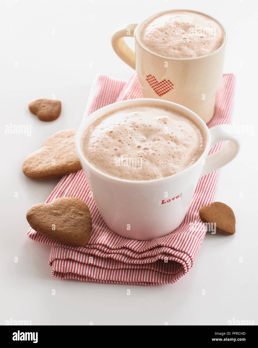 Two mugs of cappuccino on napkin with heart shape biscuits Stock Photo