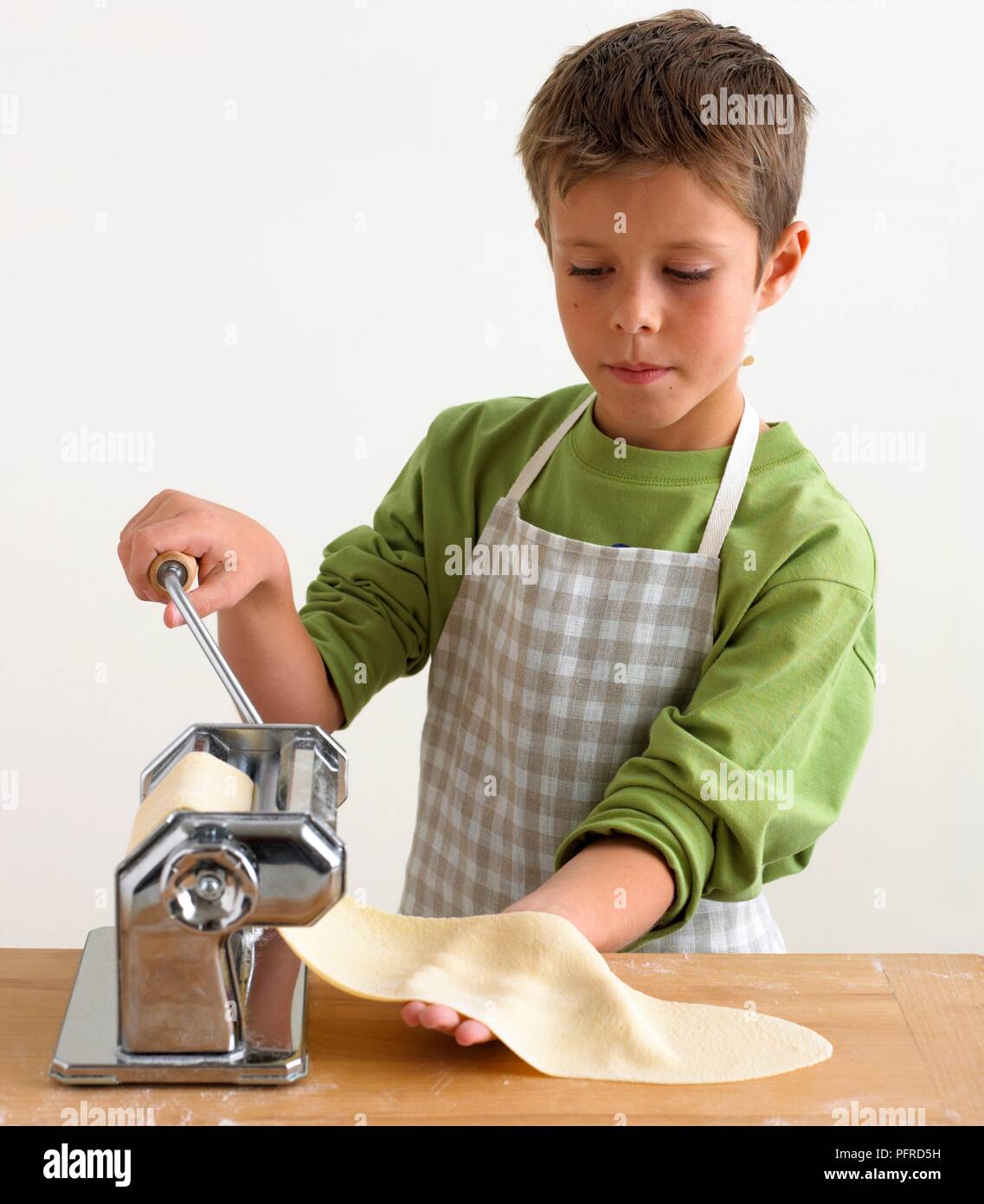 Boy rolling pasta dough through pasta machine Stock Photo Alamy