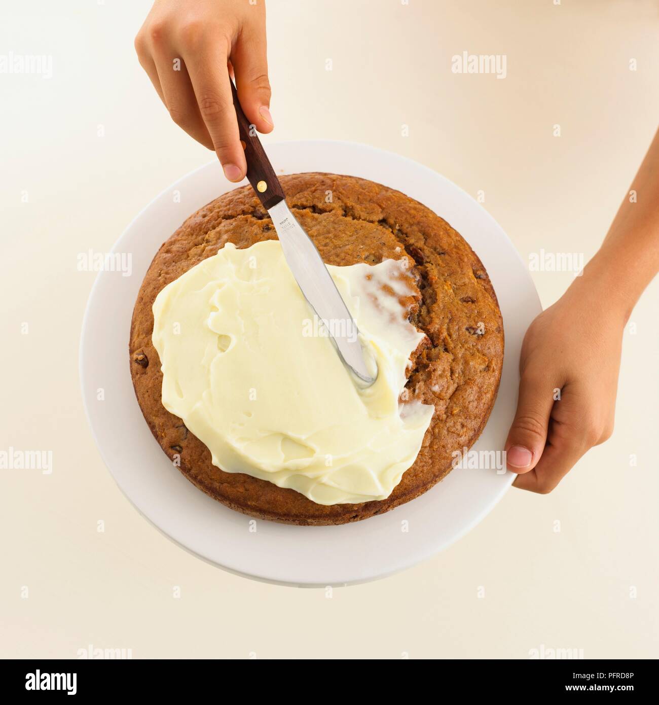 Girl's hand spreading cream cheese icing on a carrot cake using a palette  knife, close-up Stock Photo - Alamy