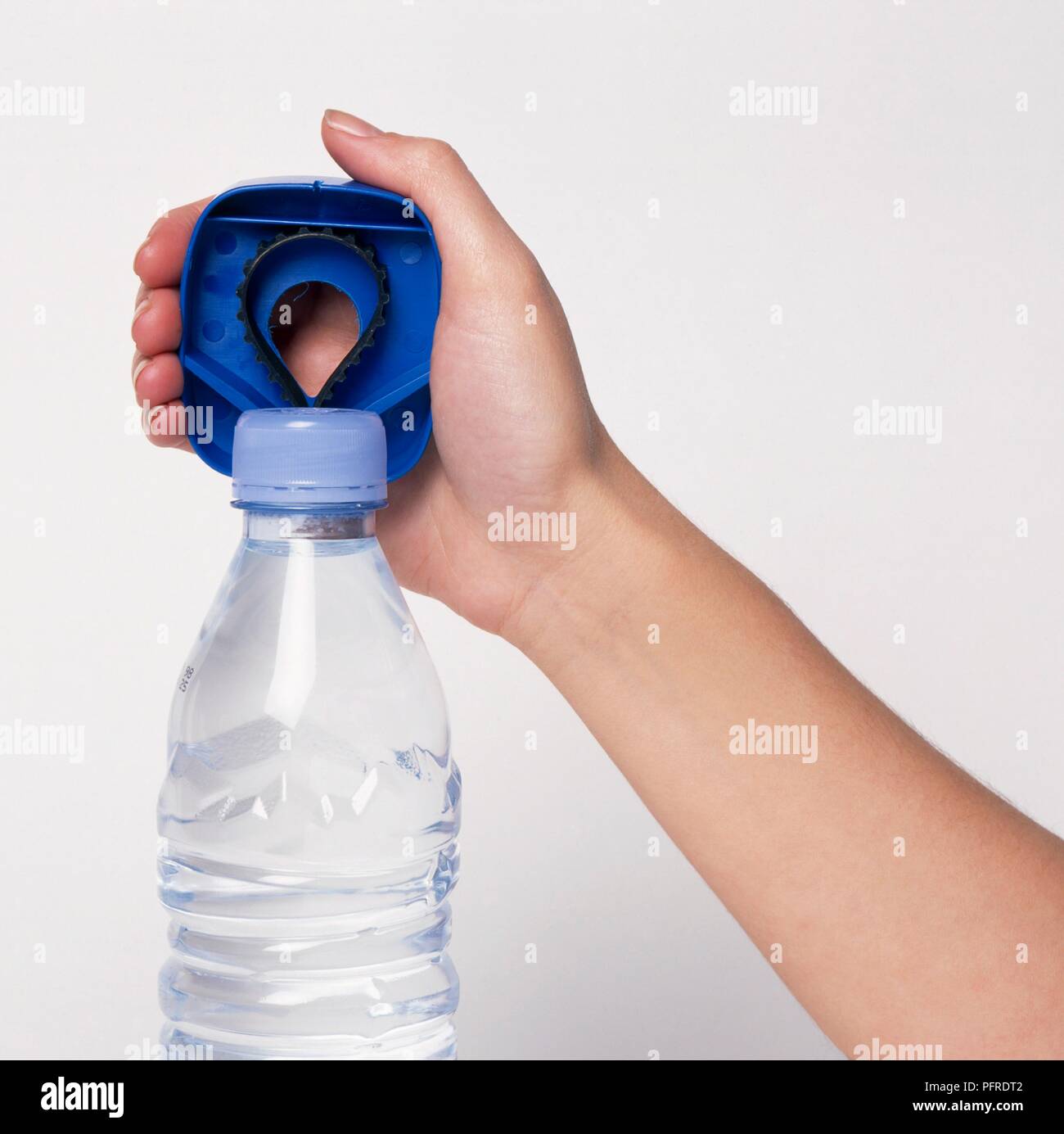 Hand holding blue plastic bottle opener above lid on bottle of water
