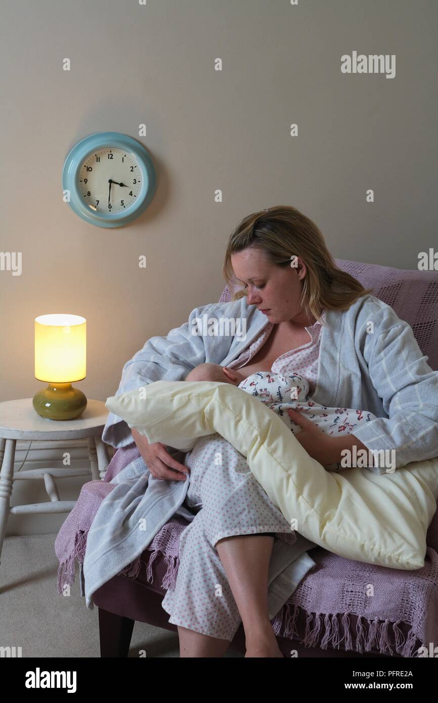 Woman seated on armchair breastfeeding a baby Stock Photo Alamy