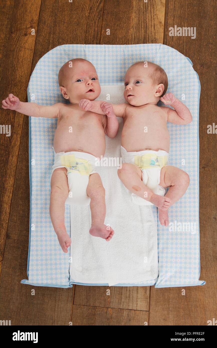 Twins, girl and boy, lying on a changing mat on the floor Stock Photo -  Alamy