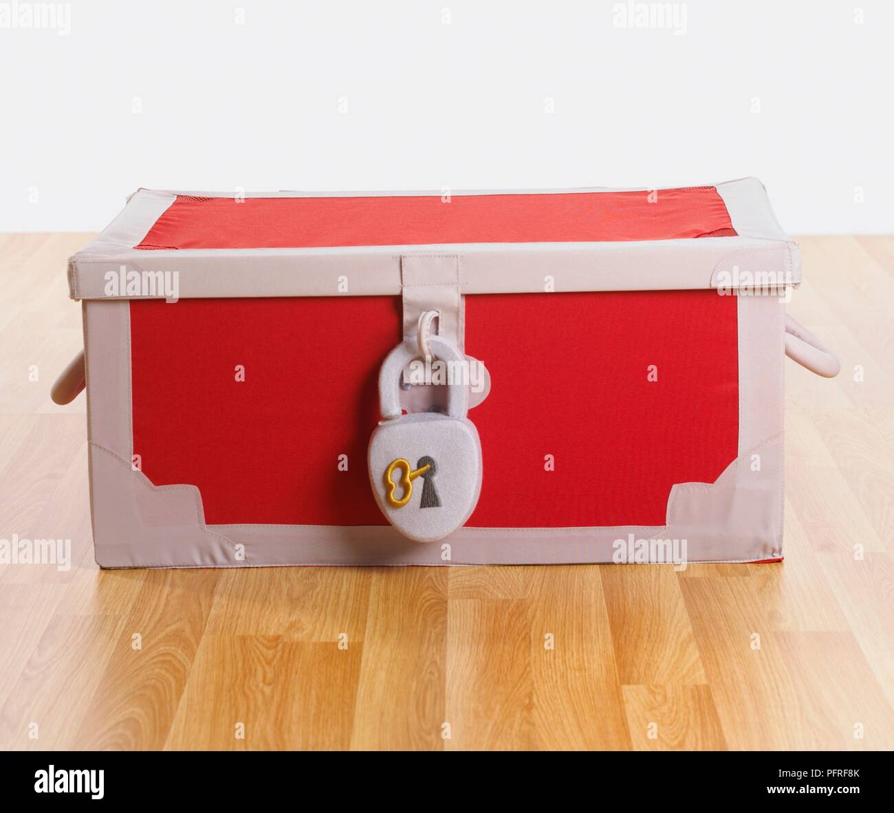 Padlocked red toy box on wooden floor Stock Photo