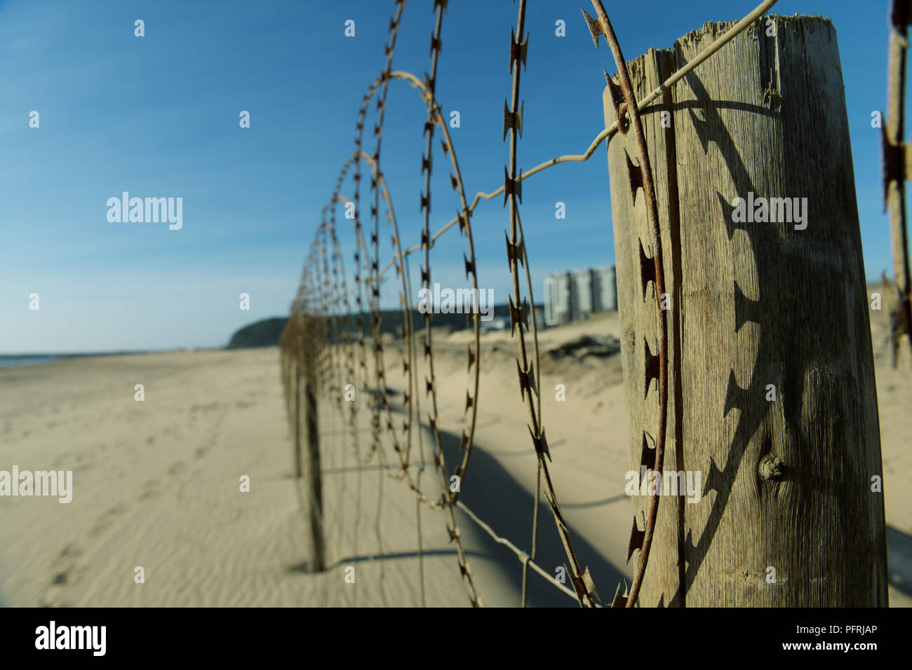 Durban, KwaZulu-Natal, South Africa, weathered fence line on beach where barbed wire is casting shadow on wooden fencepost, landscape, city Stock Photo