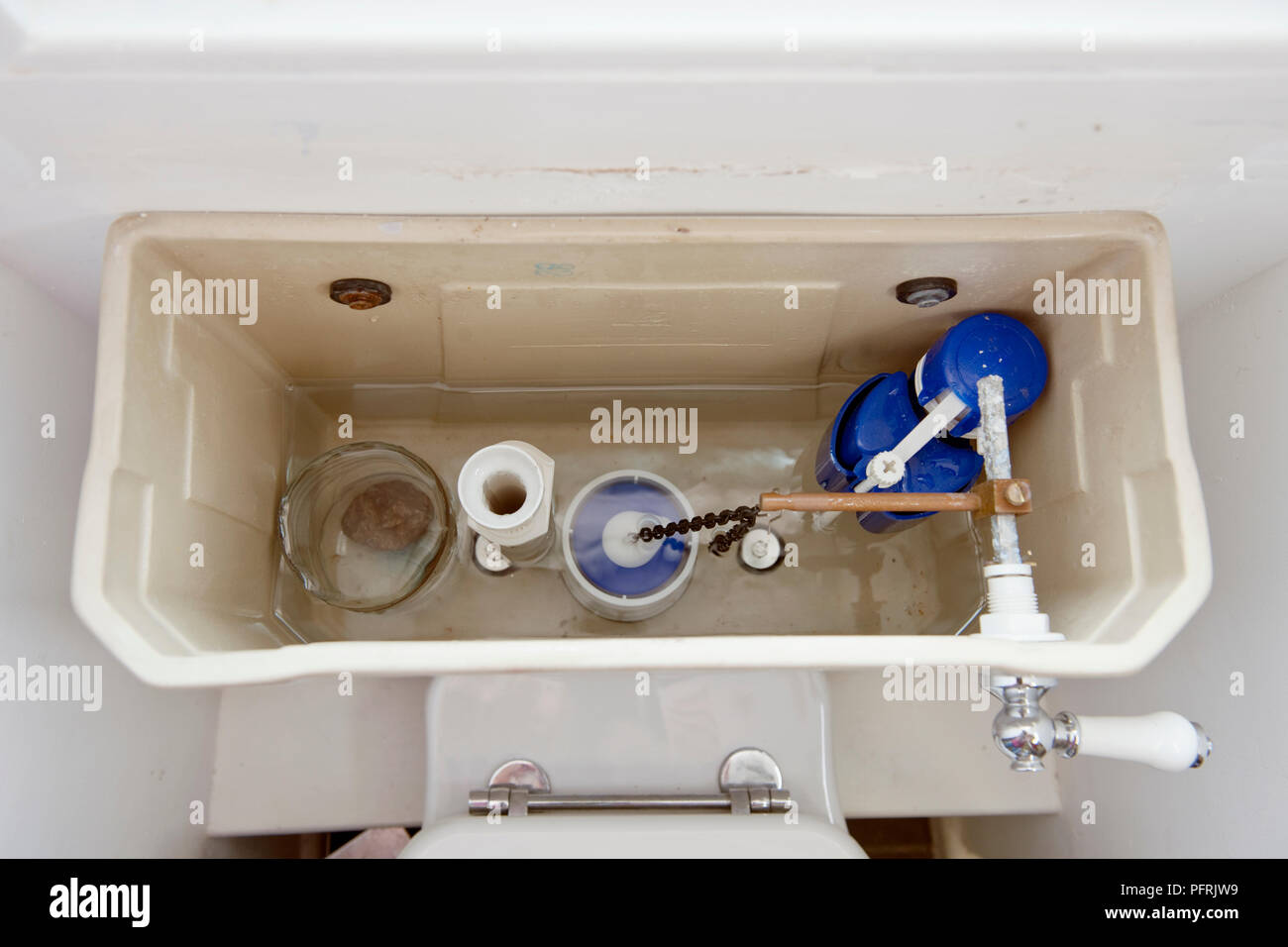Toilet cistern with home-made water saving device (a plastic water bottle  with the top cut off, placed in the cistern Stock Photo - Alamy