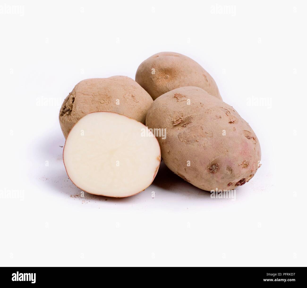 Whole and halved Red Lasoda potatoes with soil on skins Stock Photo