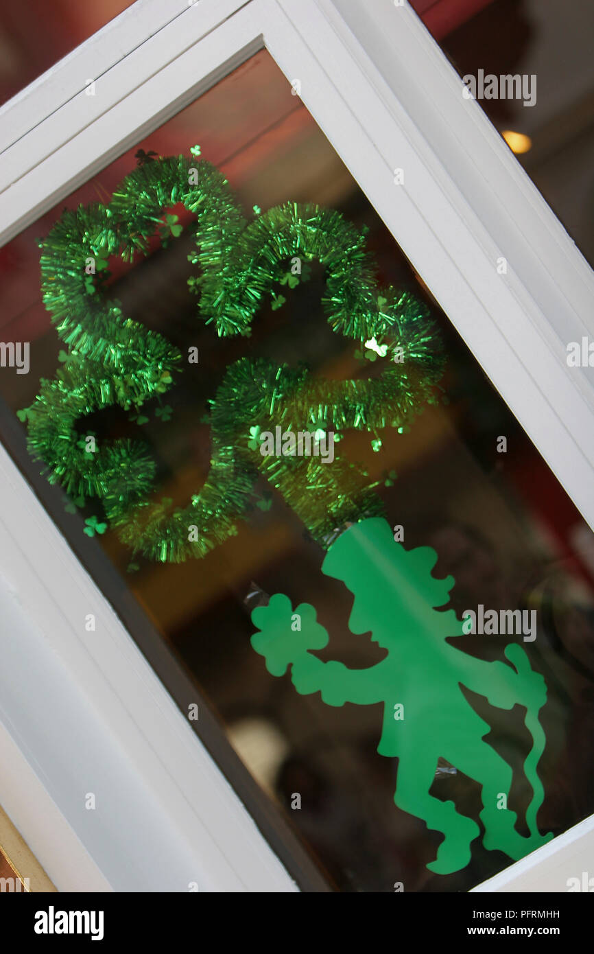 Ireland, Dublin, St Patrick's Day, tinsel shamrock and cut out figure decorations on window, close-up Stock Photo