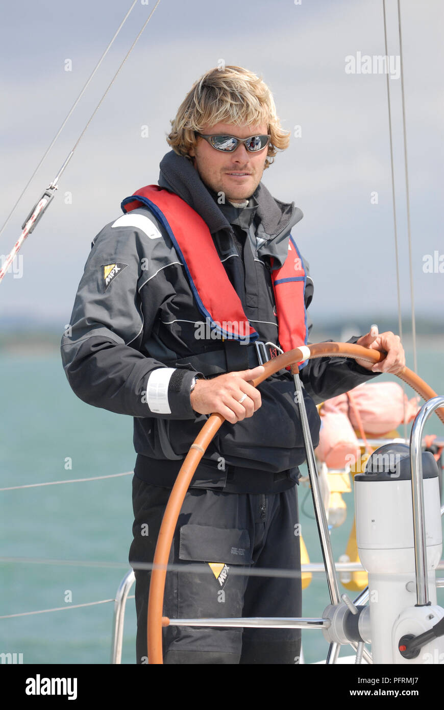 Man with sunglasses on standing at helm of a sailing boat Stock Photo