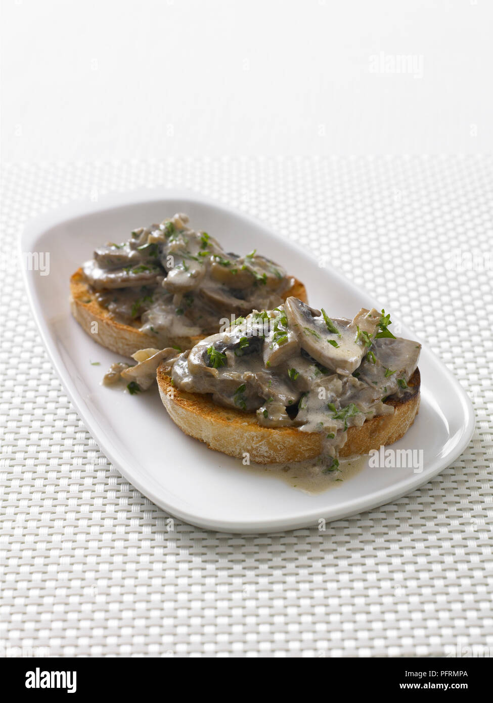 Mushroom bruschetta on white plate on table, close-up Stock Photo