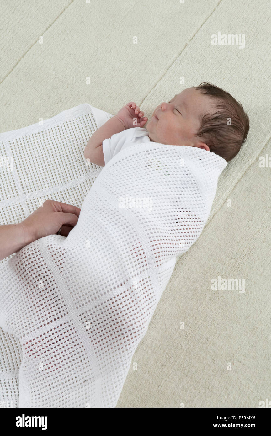 Swaddling a baby boy in a cellular blanket, close-up Stock Photo