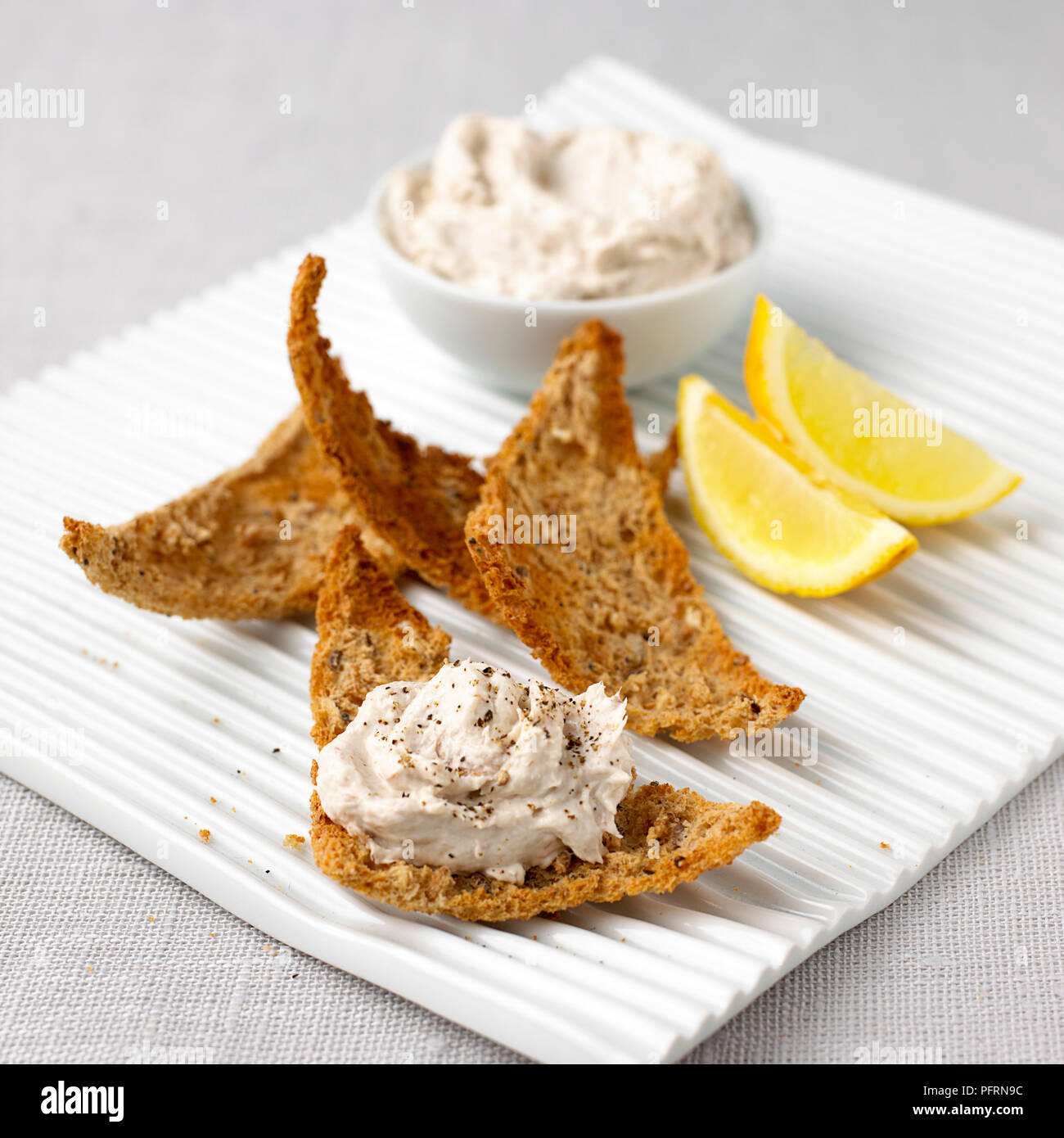 Smoked mackerel pate in bowl and on toasted brown bread with sliced