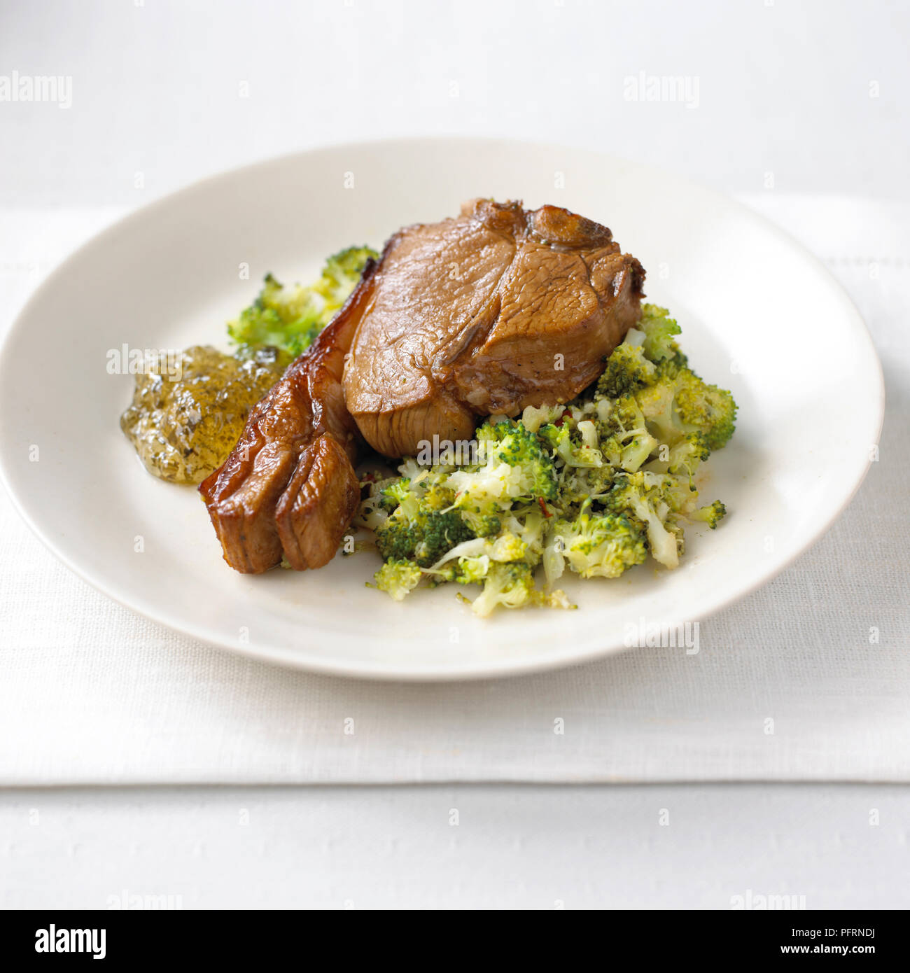 Marinated lamb chop with chilli broccoli and mint jelly served on white plate on folded napkin
