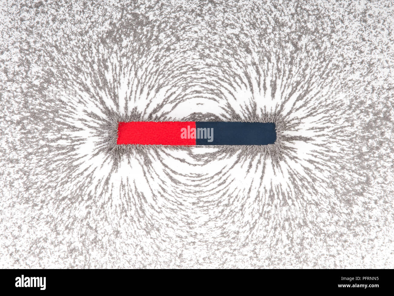 Bar magnet attracting metal filings Stock Photo