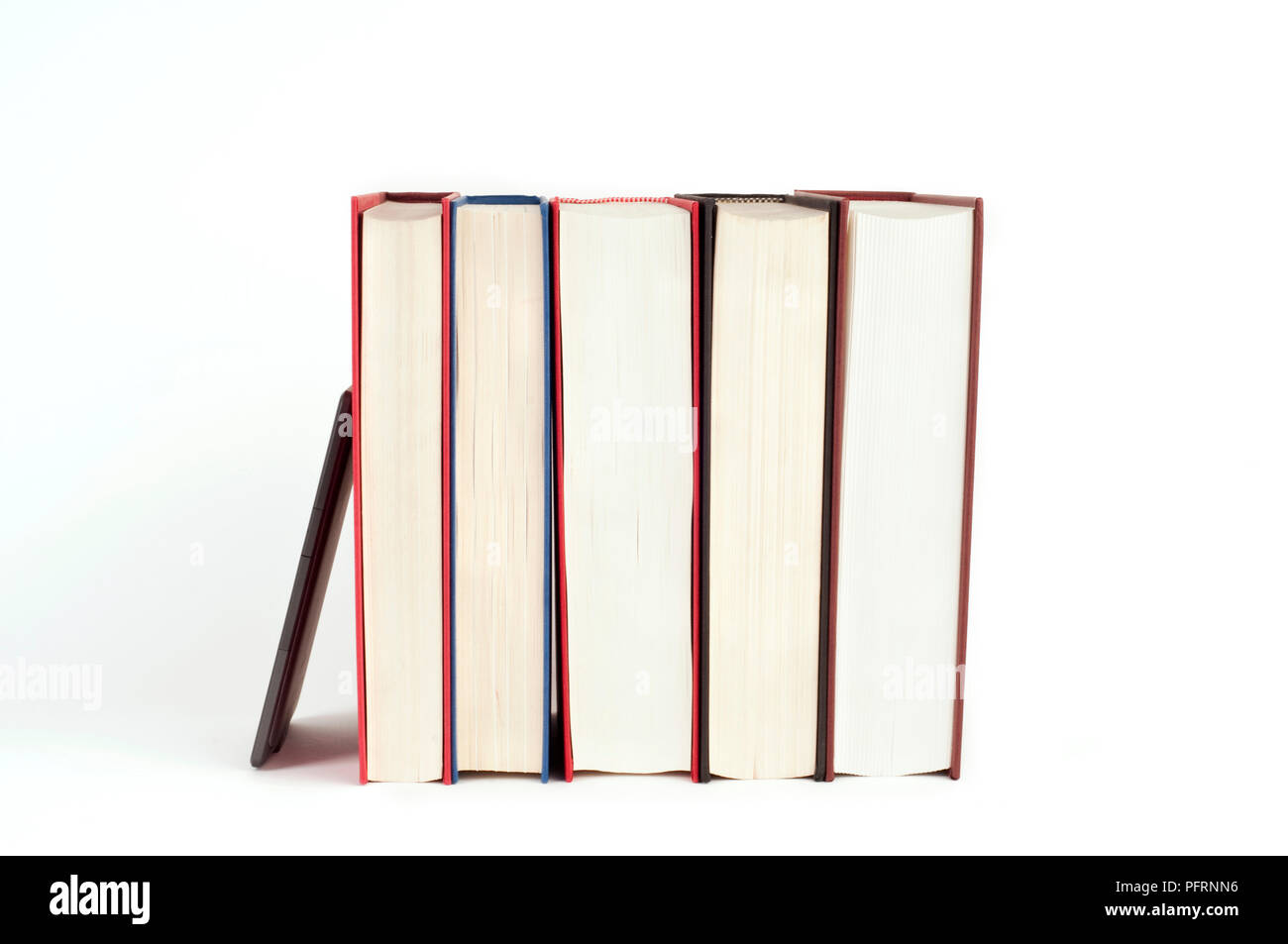 Five hardback books with their front edges facing forward, and an electronic reader Stock Photo