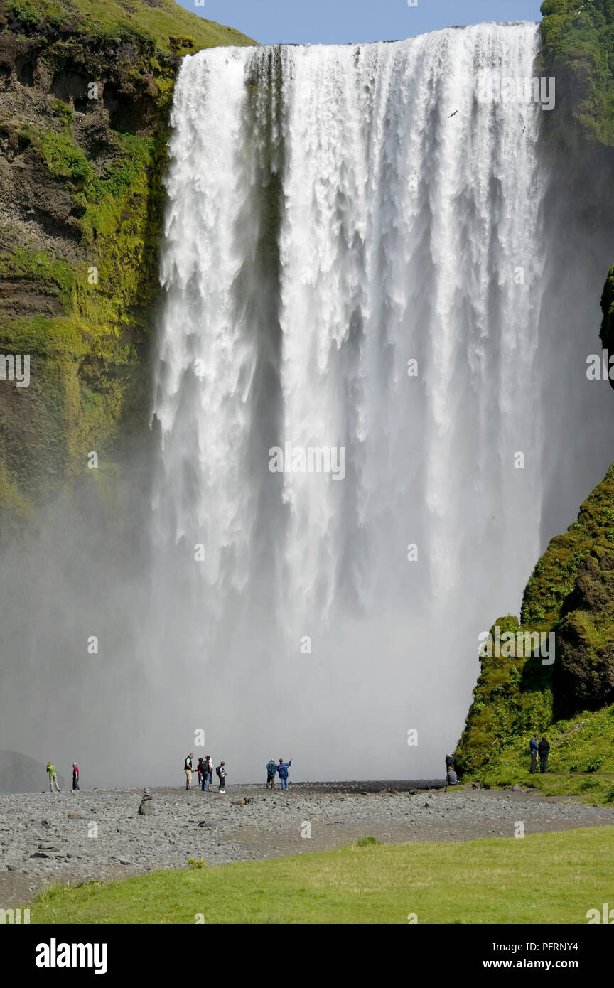 Iceland, Skogafoss (Forest Falls) visitors watching large, powerful waterfall Stock Photo