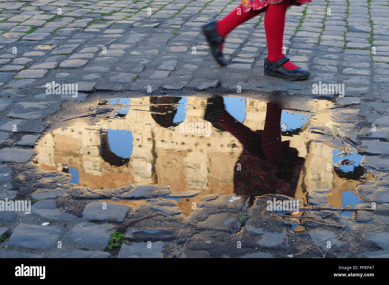 Italy, Rome, Colosseum, child running past puddle with reflection of ...
