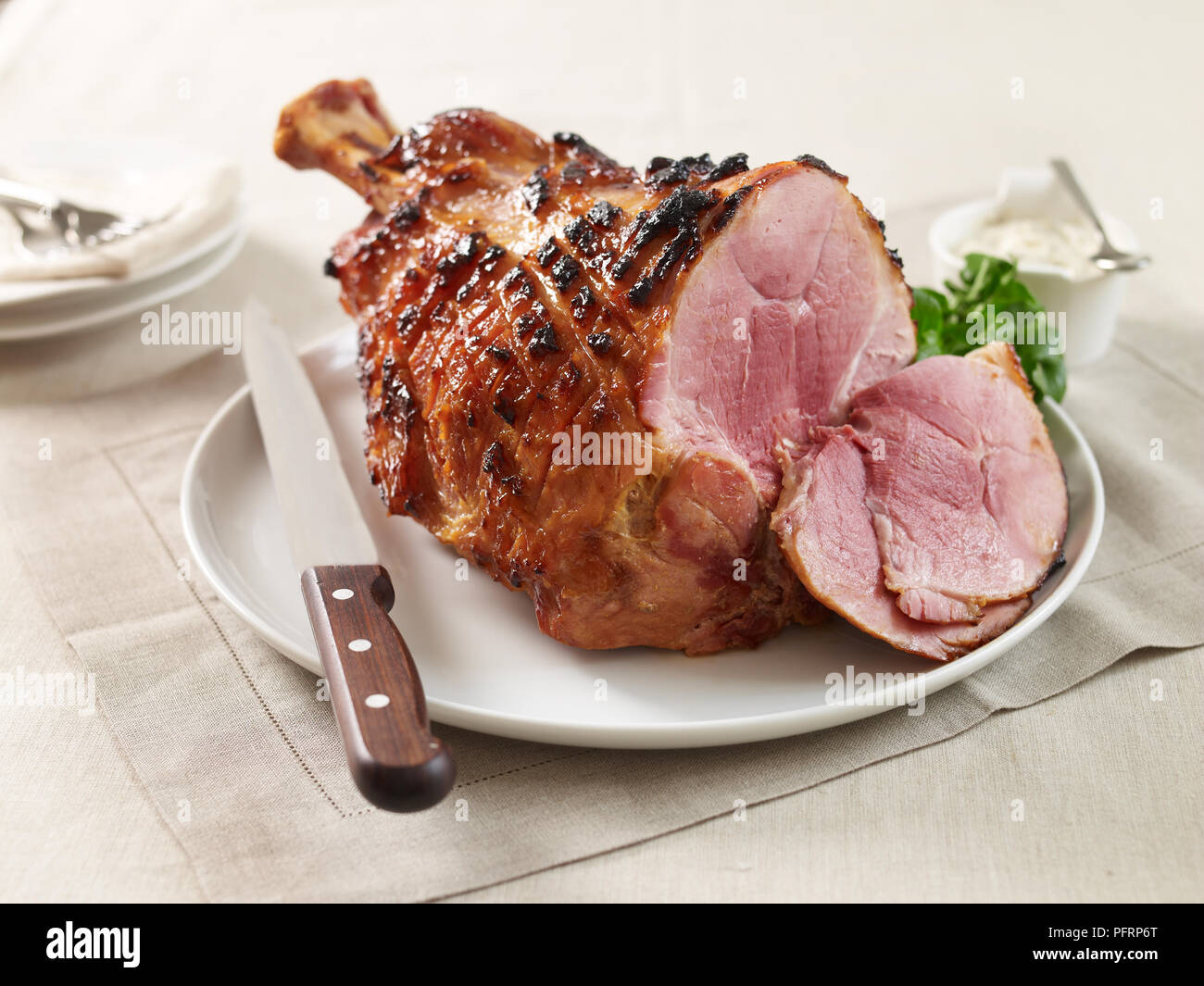 Mustard glazed ham on a plate, with a carving knife Stock Photo
