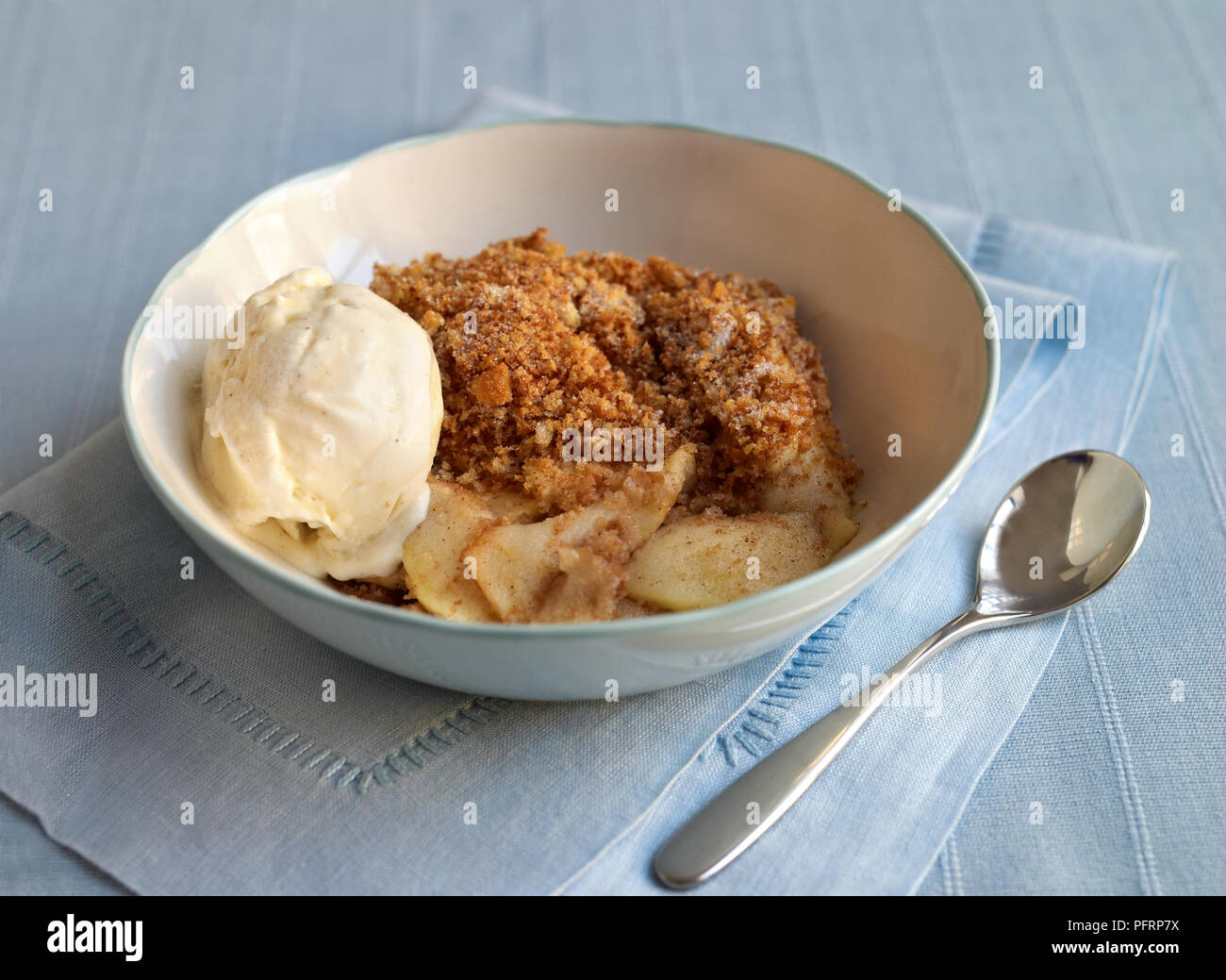 Apple Brown Betty in a bowl, spoon nearby Stock Photo