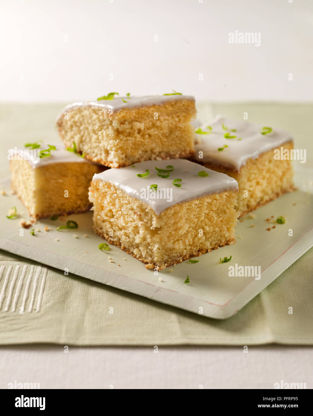 Four small, square pieces of lime cake with icing and lime zest Stock Photo