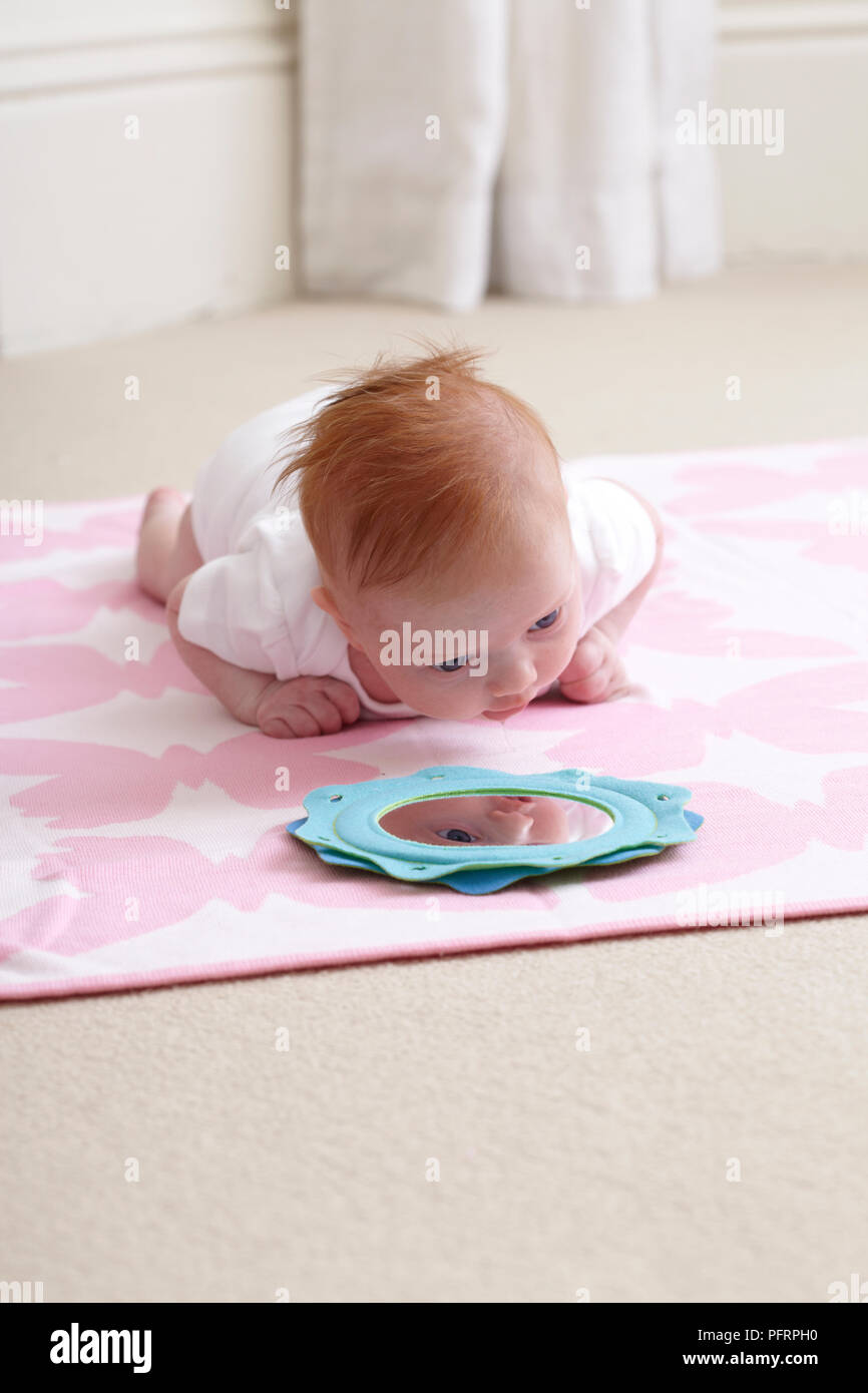 Baby Girl 8 Weeks Lying On Floor Mat Looking At Mirror In Front