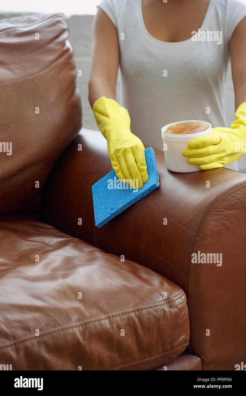 Woman Wearing Yellow Washing Up Gloves To Polish Brown Leather