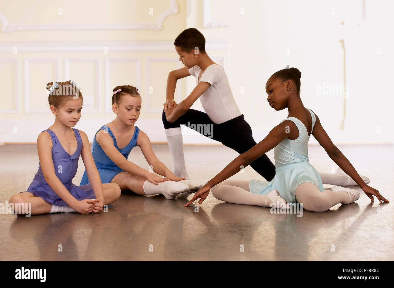 Group of young ballet dancers doing stretching exercises Stock Photo