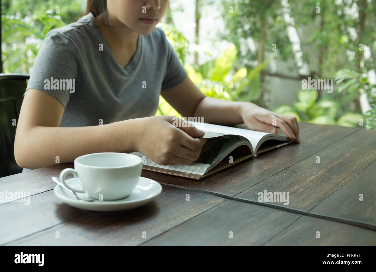 Young woman sitting on table reading a book with cup of coffee Stock ...
