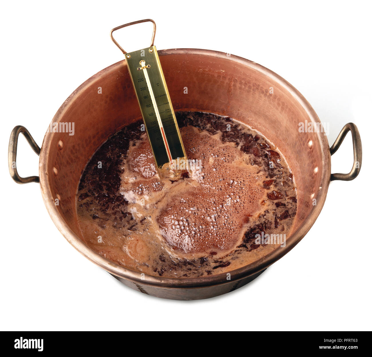 Cooking jam in copper pan, inserting thermometer to monitor the