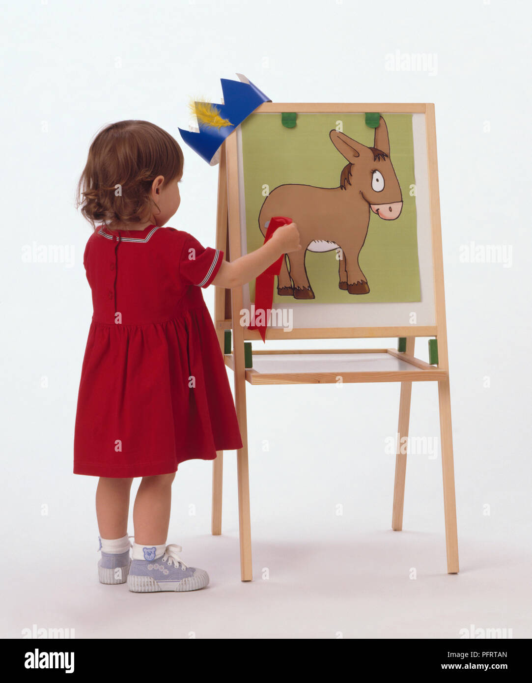 Young girl wearing red dress playing pinning tail on the donkey game on  easel Stock Photo - Alamy
