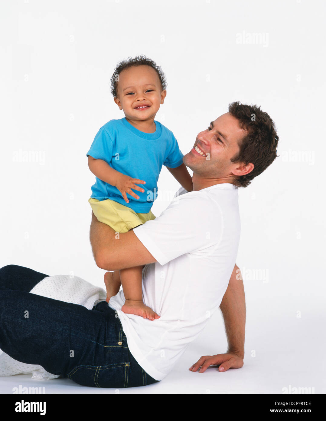 Father sitting on floor holding standing baby boy Stock Photo