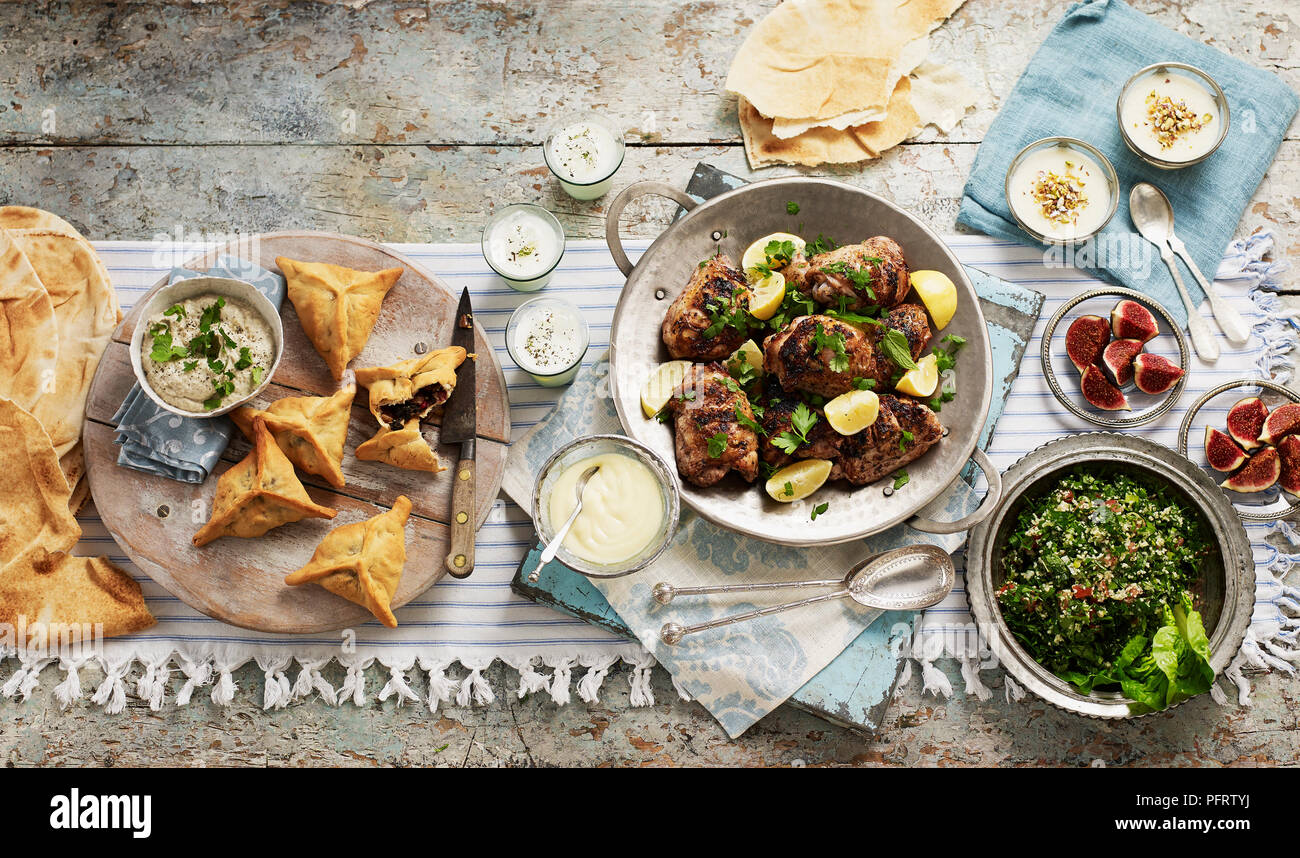 Lebanese meal for sharing, including baba ganoush (aubergine dip), fatayer bisabanikh (pastry parcels), toum (garlic sauce), laban, djaj meshwi (chicken), khubz (bread), muhallabia (milk pudding), tabbouleh Stock Photo