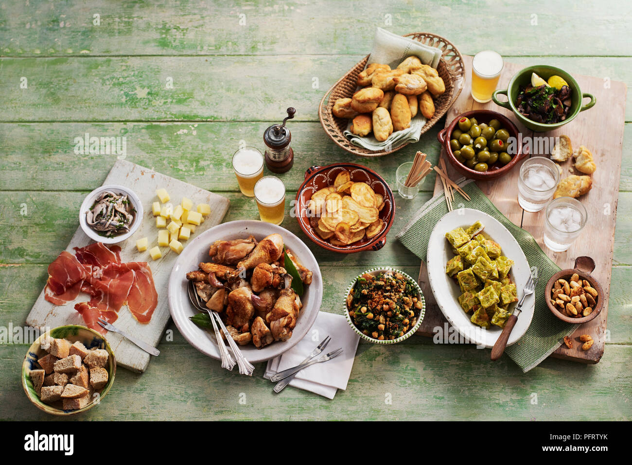 Andalucian tapas, including boquerones in vinagre (anchovies), pollo al ajillo (chicken with garlic), tostadas de garbanzos con espinacas (chickpeas and spinach), tortilla de habas (broad bean tortilla), champinones al ajillo, bolillos (bread), toasted almonds Stock Photo