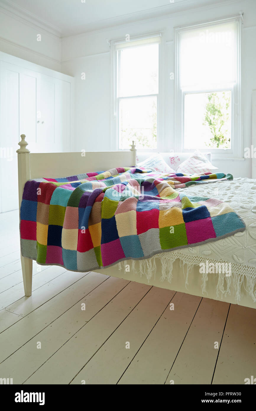 Knitted patchwork blanket on bed Stock Photo