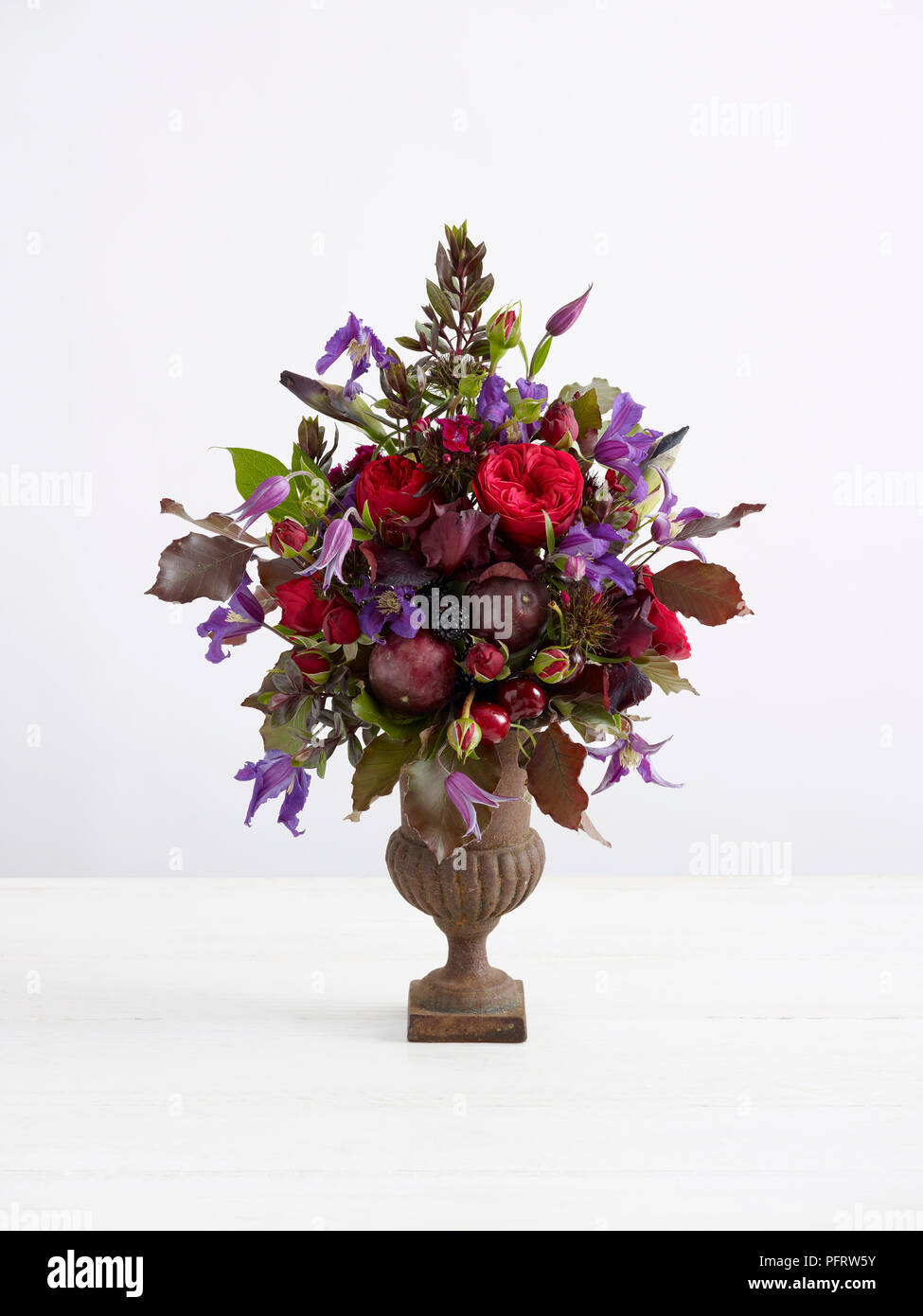 Miniature floral urn arrangement including fruit, copper beech leaves, roses Stock Photo