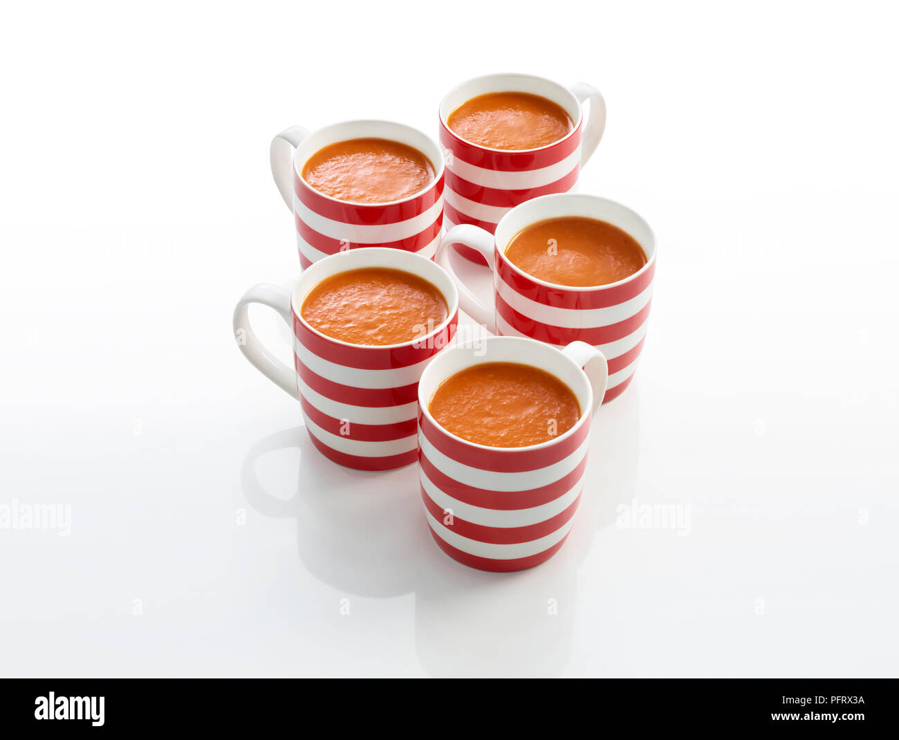 Five stripy red mugs of tomato soup Stock Photo