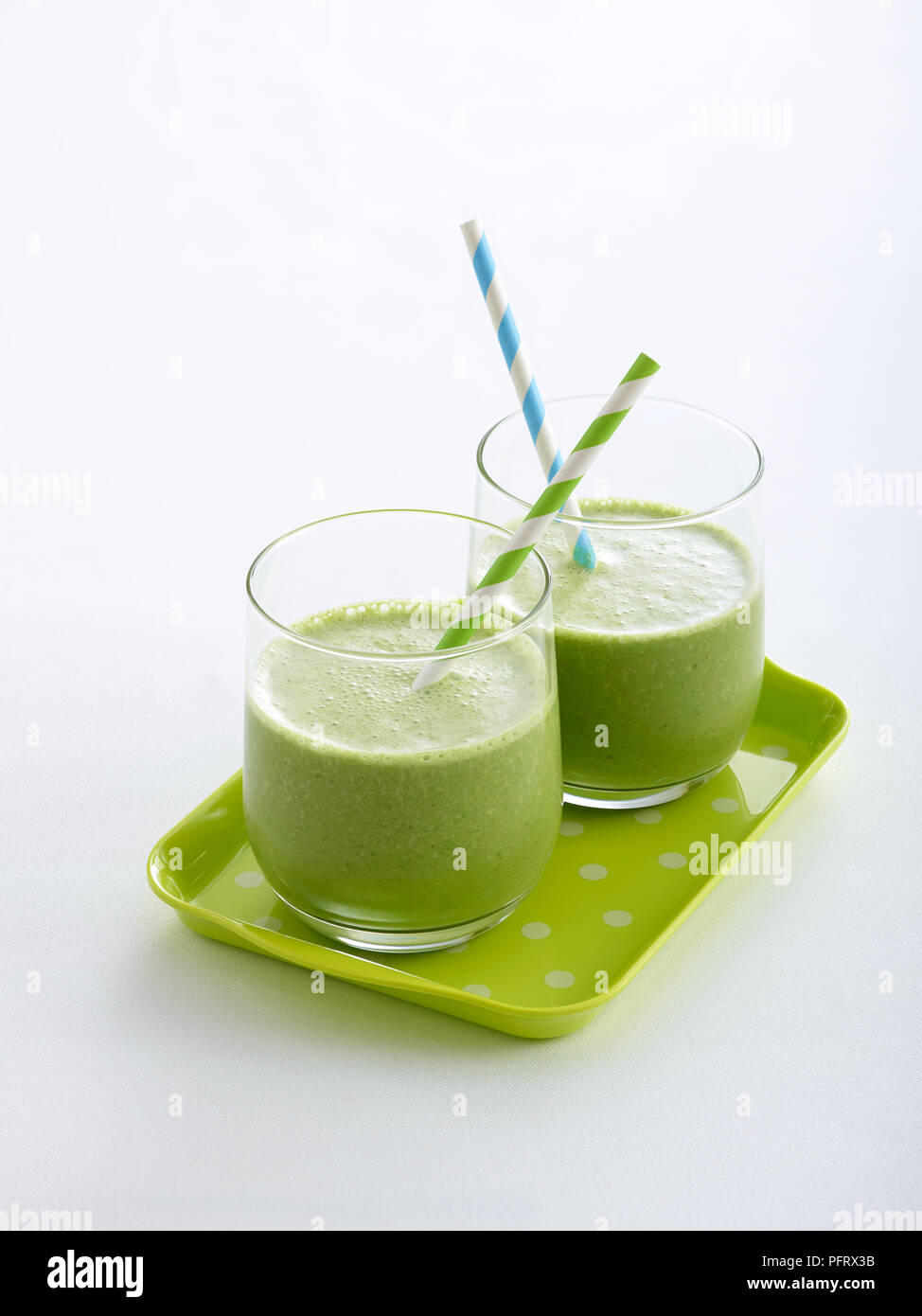 Two glasses filled with a green smoothies, served on a grey tray Stock Photo