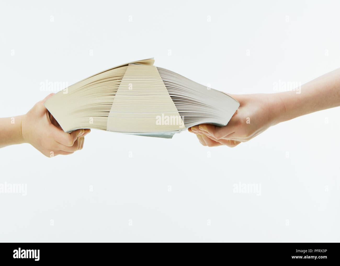 Children trying to pull two books with interleaved pages apart Stock Photo