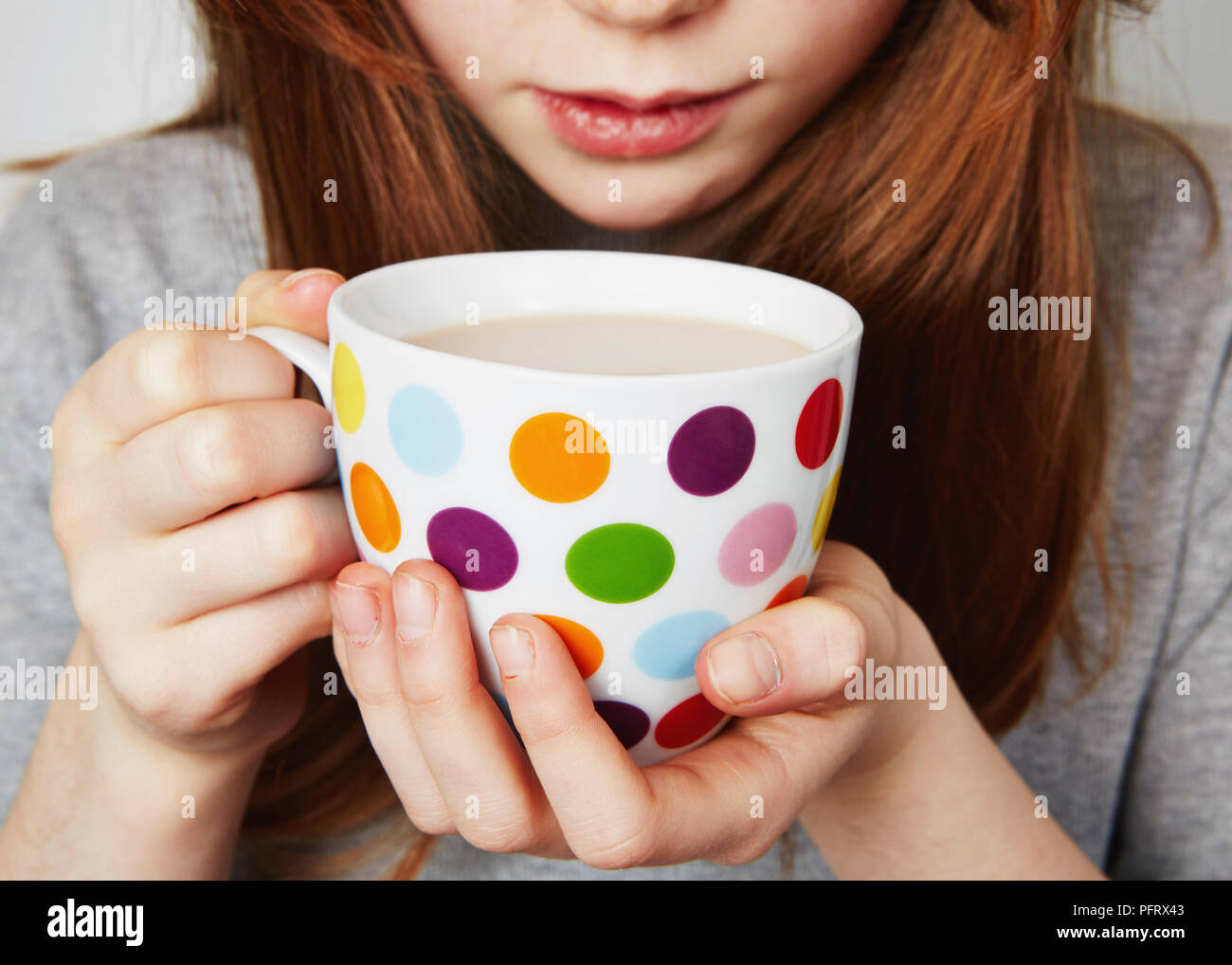 Child drinking a hot drink from a spotty mug Stock Photo