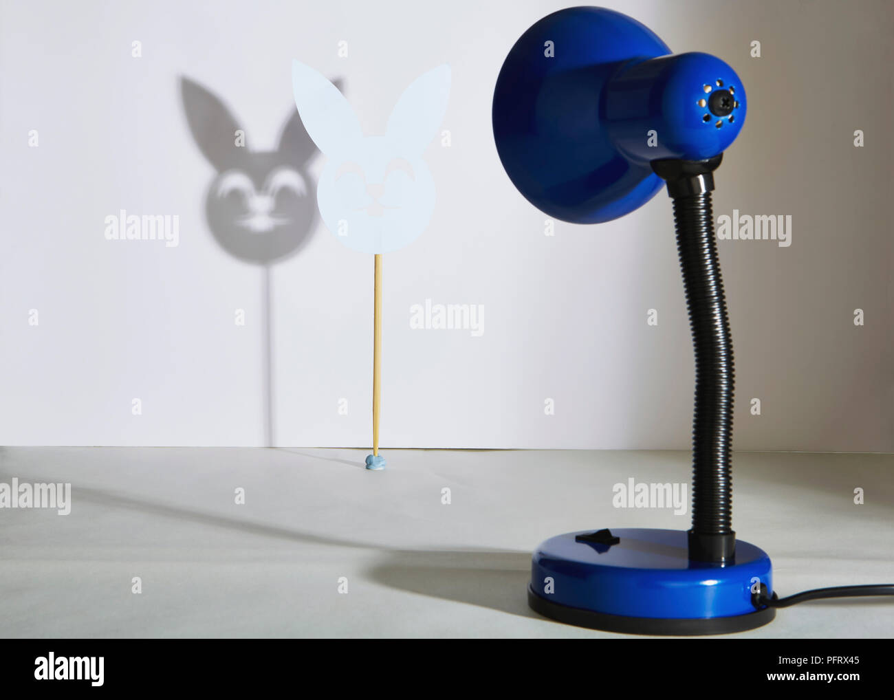 Blue table lamp casting a shadow of a rabit mask Stock Photo